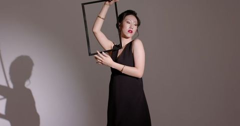 Elegant woman in black dress holding rectangular frame