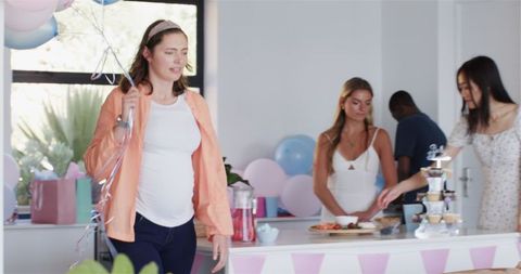 Friends Celebrating Baby Shower with Balloons and Snacks
