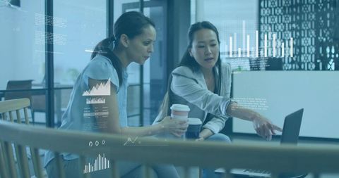 Businesswomen Analyzing Data on Laptop in Modern Office Lounge