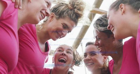 Cheering women sports team huddling in bright pink tops celebrating teamwork and sunny joy