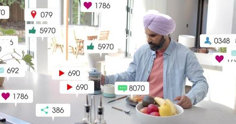 Man in turban pouring French press coffee at kitchen island with social media notifications