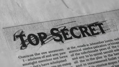 Top secret stamp on aged document with handwritten scribbles and grunge monochrome texture