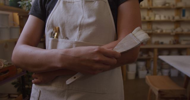 Potter Holding Brush in Ceramic Workshop with Apron - Download Free Stock Images Pikwizard.com