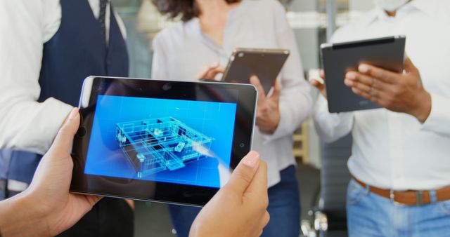 This image depicts a diverse group of professionals analyzing an architectural blueprint displayed on digital tablets. The scene conveys a modern office environment with a focus on teamwork, collaboration, and technology. Ideal for illustrating topics related to business innovation, project planning, architectural design, and modern workflows in a corporate setting.