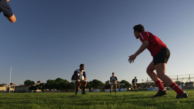 Teenagers in rugby competition wearing team uniforms, showcasing throws and catches during a lively outdoor match. Suitable for use in sports promotions, athletic campaigns, or educational materials highlighting teamwork and sportsmanship.