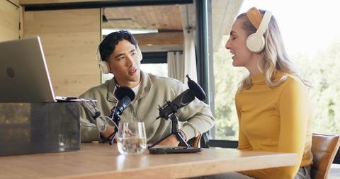Co-hosting podcast asian man and woman recording conversational interview in sunlit studio