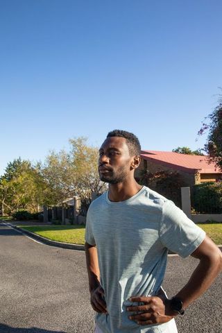 Runner pausing to check watch in suburban neighborhood