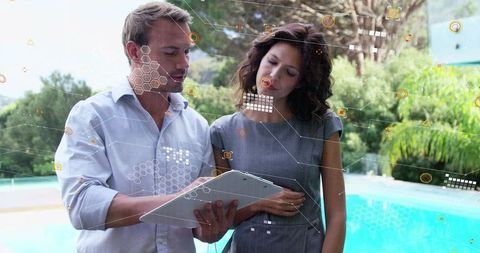 Business colleagues collaborating over tablet by pool with augmented data HUD overlay
