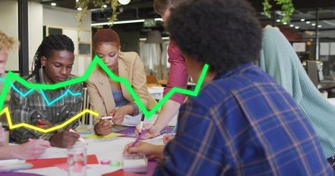 Creative team collaborating on marketing layouts with data chart overlays in open office