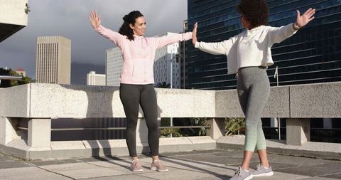 Women stretching together on rooftop workout hoodies leggings urban fitness partners
