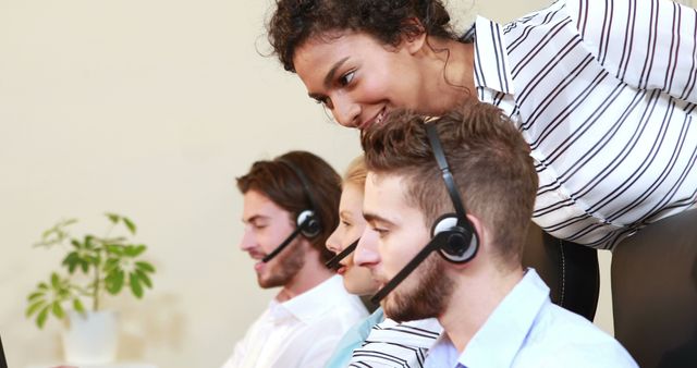 A diverse group of young professionals, including Caucasian and African American individuals, are working in a call center environment, with copy space. They are equipped with headsets, suggesting they are engaged in customer service or telemarketing activities.