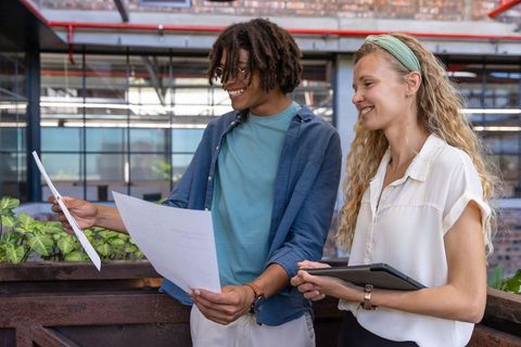 Colleagues Reviewing Documents on Office Balcony with Greenery