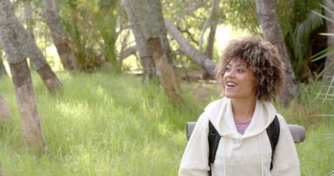 Smiling woman enjoying sunny day in lush park setting with greenery
