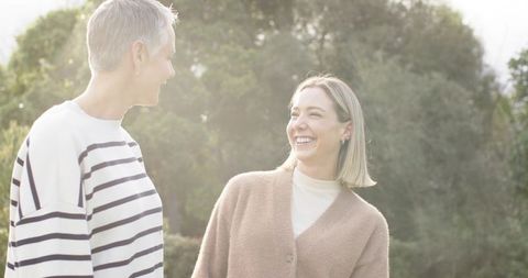 Sunlit friends smiling and chatting in park during golden hour showing warm companionship