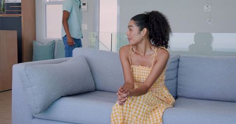 Woman in Yellow Dress Seated Indoors as Man Leaves