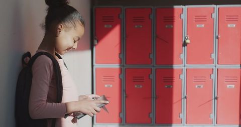 Smiling African American Girl Using Tablet by Red School Lockers