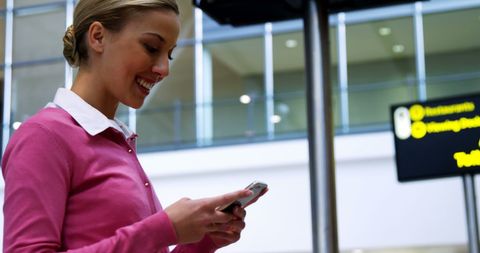 Smiling Woman Texting on Phone at Modern Airport