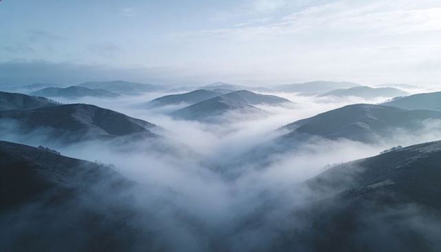 Unfolding Fog-Filled Mountain Valleys Over Rolling Grassy Ridges at Dawn Light