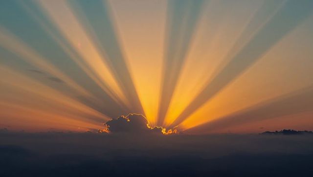 Golden Sunrise with Radiating Sun Rays Above Horizon