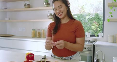Smiling Asian Woman Enjoys Preparing Fresh Ingredients in Modern Kitchen