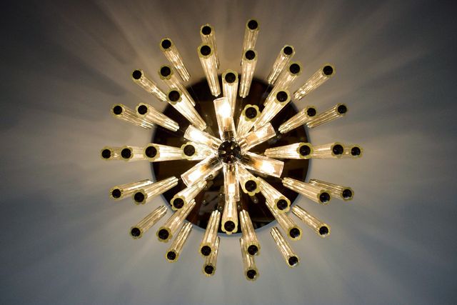 Staring up at modern chandelier emitting light through multiple exposed bulbs. Great for illustrating concepts of modern home decor, interior design, lighting fixtures, luxury living spaces, and architectural elegance. Can be used for websites, home improvement magazines, or interior design portfolios.