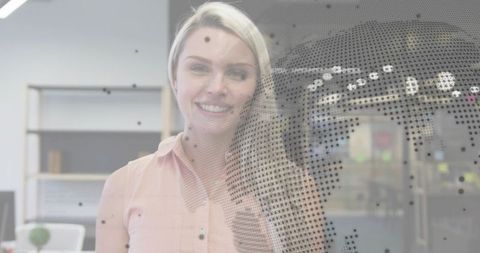 Smiling professional woman standing in modern open office with dotted globe glass overlay