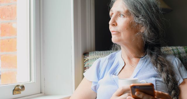 Senior Woman Relaxing with Coffee and Smartphone by Sunny Window - Download Free Stock Images Pikwizard.com