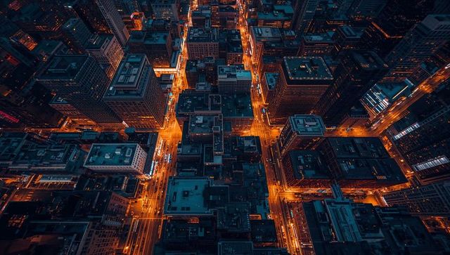 Downtown grid glowing at night from aerial drone showing neon traffic trails