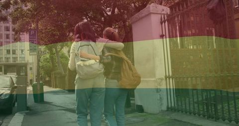 Teenagers walking upright on city sidewalk with linked arms