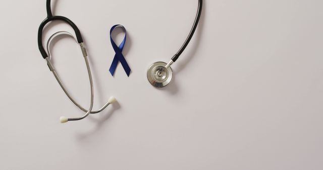 Image of stethoscope and dark blue colon cancer ribbon on white background. medical and healthcare awareness support campaign symbol for colon cancer.