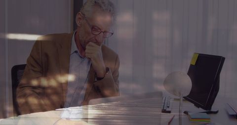 Mature Businessman Analyzing Data on Laptop in Office