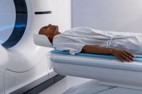 African american man lying in mri scanner wearing hospital gown undergoing diagnostic scan