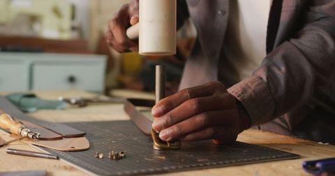 Craftsman creating leather belt with traditional tools