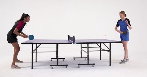 Diverse Female Athletes Competing Intently in Table Tennis Match