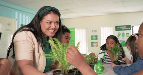 Diverse teacher guiding students planting seedlings in hands-on classroom gardening