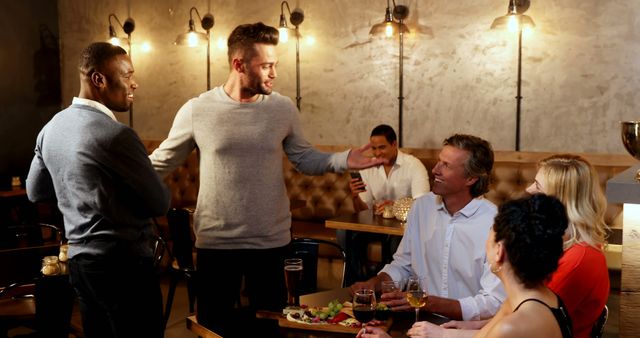Group of friends enjoying night out at a casual restaurant, socializing and laughing. Ideal for use in advertisements, social media posts, or articles about friendship, dining out, and leisure activities.