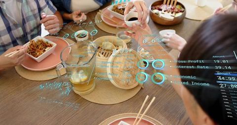 Friends sharing noodles with augmented reality financial dashboard over casual dining table
