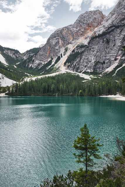Turquoise lake surrounded by pine trees and rugged mountain peaks. Ideal for promoting travel, nature retreats, or outdoor adventures. Perfect for background imagery in publications and websites focused on landscapes and scenic views.