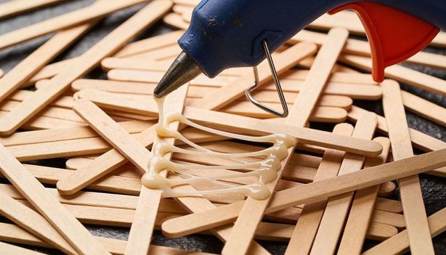 Closeup of hot glue gun bonding wooden craft sticks for diy projects and texture study