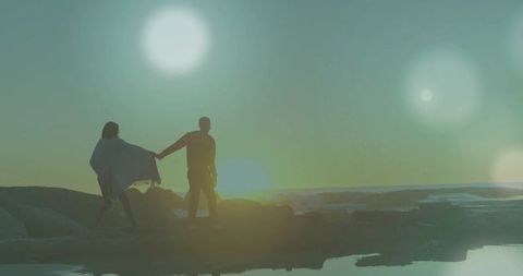 Couple enjoying romantic sunset walk on rocky shore