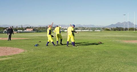 Baseball teammates celebrating victory on suburban field with umpire observing after scoring run