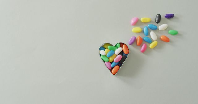 Bright and colorful candy jelly beans spilling out of a heart shaped tin evoke feelings of fun, sweetness, and love. Perfect for use in Valentine’s Day promotions, candy advertisements, blog posts on confectionery, or any creative project requiring bright, cheerful imagery.