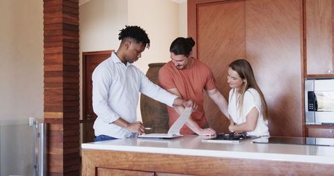 Diverse Friends Discussing Plans in Kitchen with Tablet