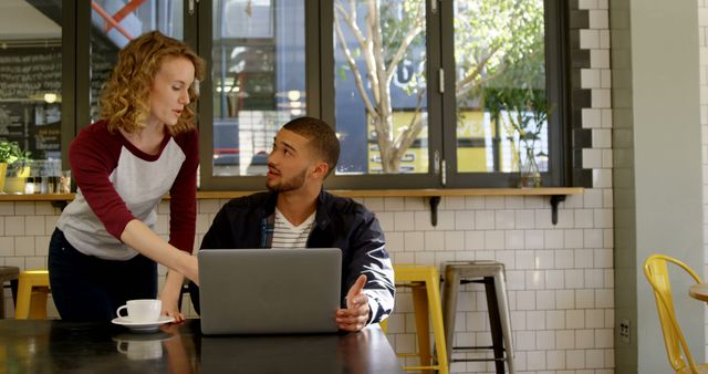 Young colleagues discussing project over laptop in modern coffee shop - Download Free Stock Images Pikwizard.com