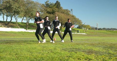 Female athletes training agility outdoors in park setting