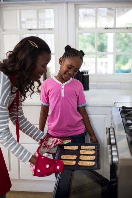 Mother and daughter baking cookies together, showcasing family bonding and culinary activity. Suitable for themes related to family life, parenting, home cooking, and domestic activities. Great for advertisements, educational materials, or lifestyle blogs focusing on family dynamics and home cooking.