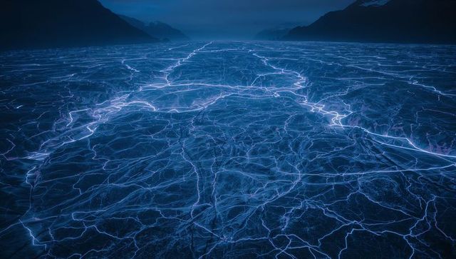 Glowing Blue Cracked Icefield Stretching to Mountain Horizon at Twilight