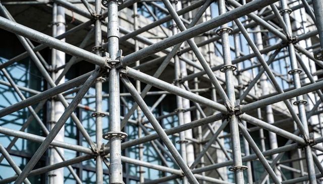 Galvanized scaffolding lattice framing glass facade, industrial construction geometry