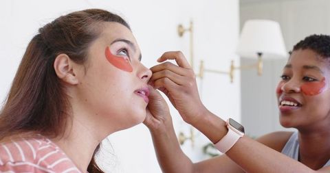 Friends applying under-eye hydrogel patches during at-home skincare session
