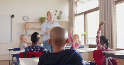 Engaged Students Raising Hands in Classroom with Friendly Teacher